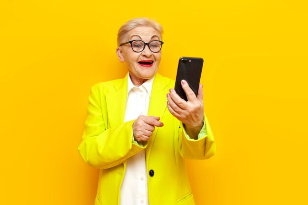 funny old business granny in blazer and glasses using smartphone online and laughing