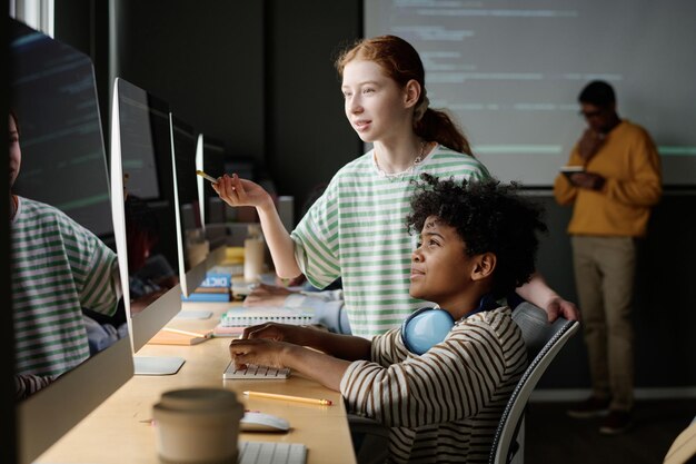 Girl helping classmate during it lesson