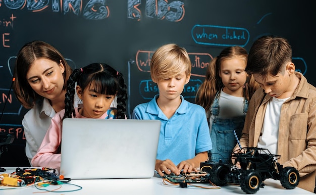 Girl wear pink cloth use laptop for coding while teacher watch her erudition