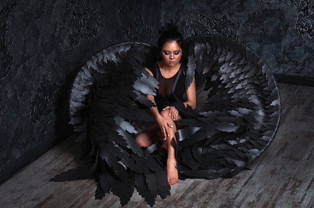 girl with black angel wings in a dark room.