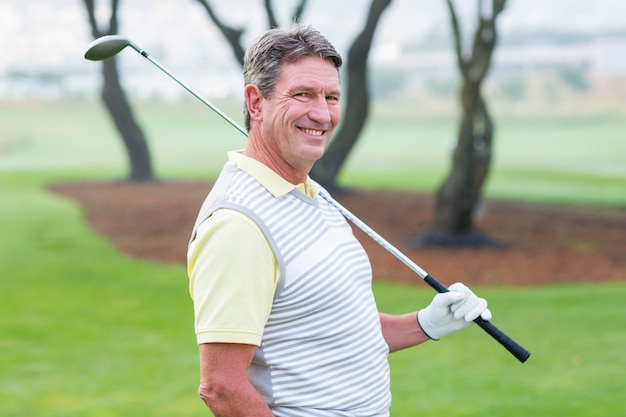 golfer standing and swinging his club smiling at camera 