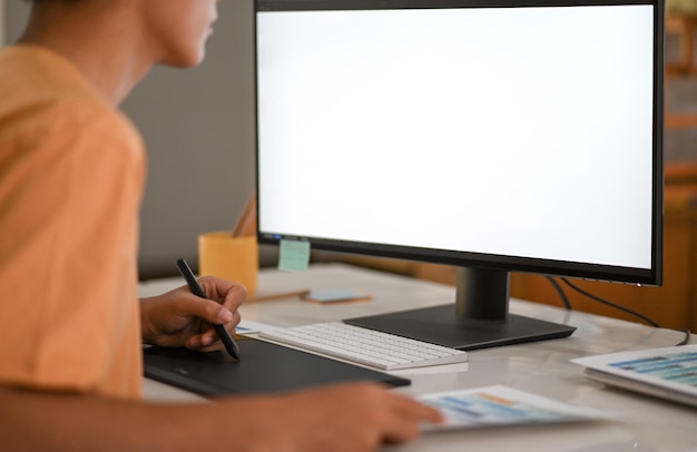 Graphic designer working on digital board with mockup computer monitor blank screen