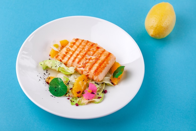 grilled salmon fillet steak with salad garnish in white plate