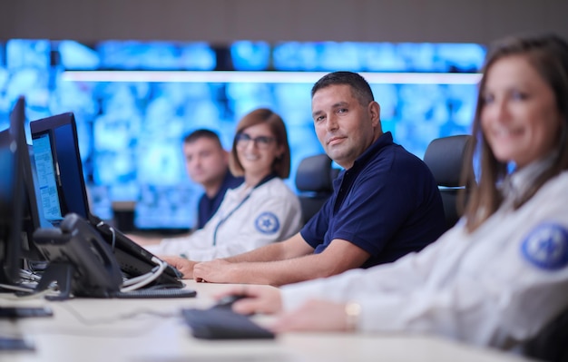 Group of Security data center operators working in a CCTV monitoring room looking on multiple monitors  Officers Monitoring Multiple Screens for Suspicious Activities  Team working on the System Contr