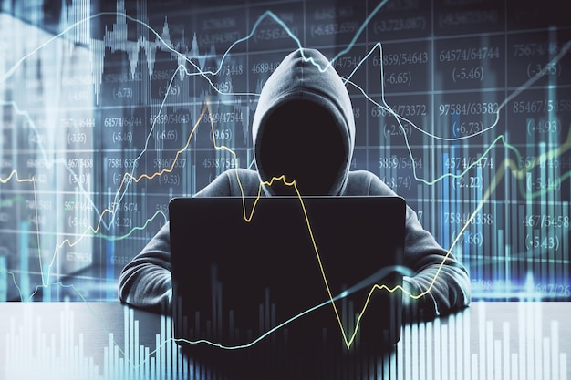 Hacker at desktop using laptop with forex chart on blurry office background Malware and finance concept Double exposure