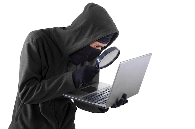 hacker looking at laptop through magnifying glass against white background