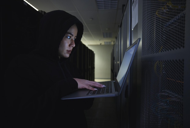 Hacker server room and woman computer coding data center crime and ransomware of cyberpunk in dark Laptop hacking person or thief in cybersecurity information technology and criminal programmer