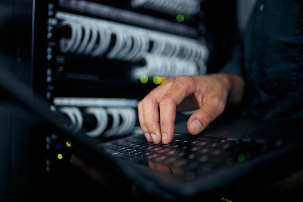 Hands laptop and typing in server room man and inspection with coding analysis and night for programming Information technology expert computer and keyboard for database solution or maintenance