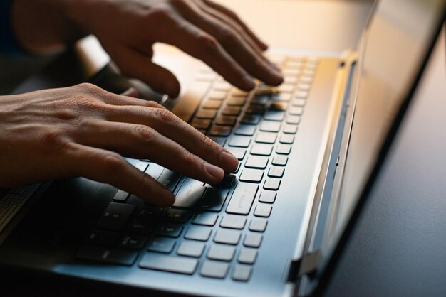 hands of a man working on a laptop closeup
