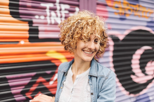 happy woman walking against graffiti on shutters