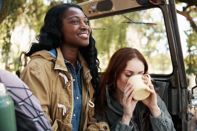 happy women tea or relax on road trip in nature or travel adventure for leisure in countryside ladies drinking and coffee in suv on summer holiday care and bonding together for tourism in texas