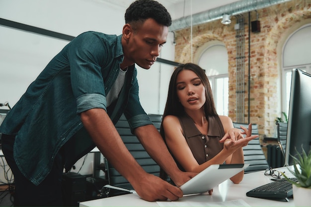 Here39s what you have to do Young beautiful woman explaining something to her coworker while working in modern office