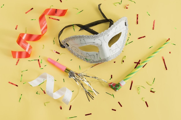 High angle view of multi colored streamers and carnival mask on yellow table