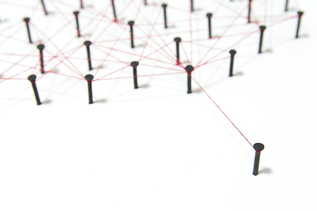 High angle view of nails connected with thread on white background