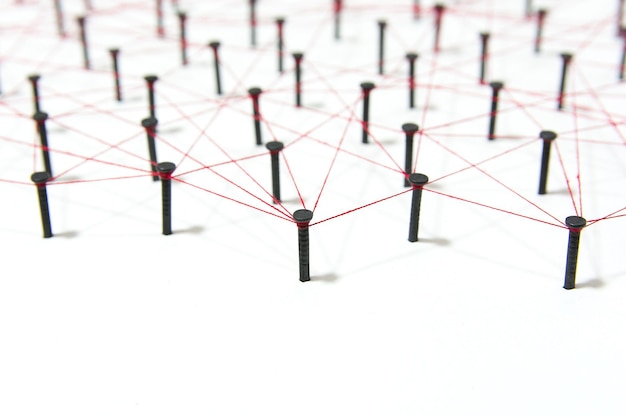 High angle view of nails connected with thread on white background