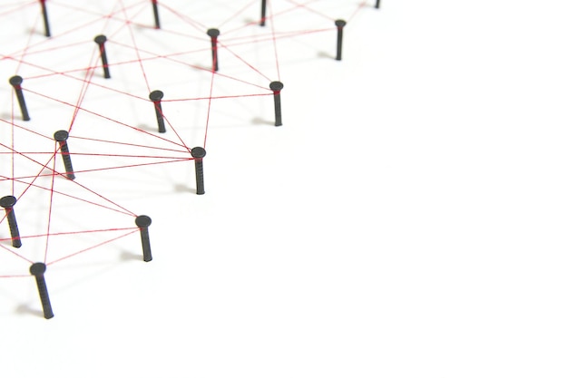 High angle view of nails connected with thread on white background
