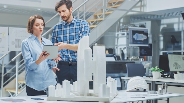 In Architectural Bureau Architect and Engineer Talking Working on a Building Complex Prototype Project Using City Model and Computers Running 3D CAD Software Residential or Business District