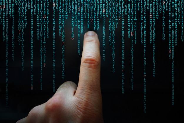 index finger pointing at digital screen binary code