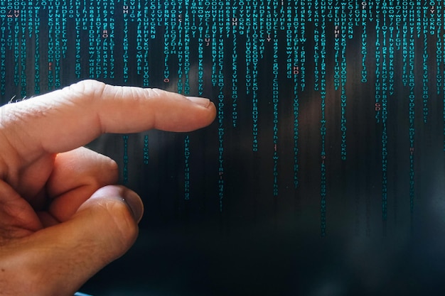 index finger pointing at digital screen binary code