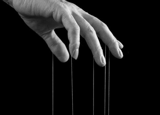Influence manipulation concept Man hand with strings on fingers Male suffering from drug gambling internet addiction or physical emotional stress Black and white