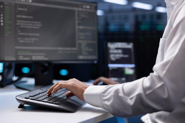 IT administrator working on PC in hardware room housing server rackmounts