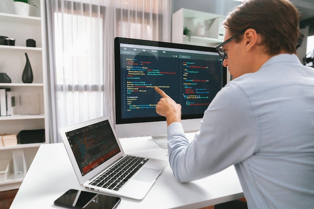 It developer pointing on coding software on pc comparing laptop pecuniary