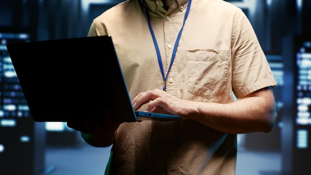 IT developer using laptop to audit energy consumption across server farm components and distributors. Programmer making sure data center hardware temperature sensors are performing flawlessly, close u