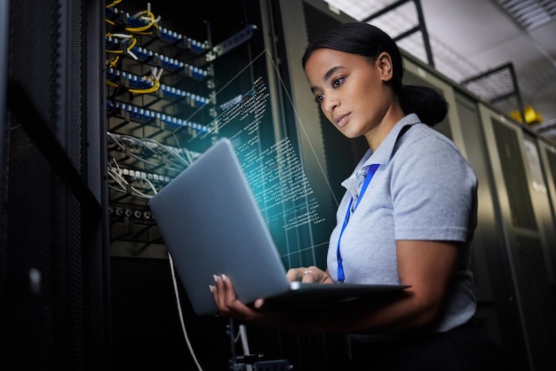 Laptop network and data center with a black woman it support engineer working in a dark server room Computer cybersecurity and analytics with a female programmer problem solving or troubleshooting