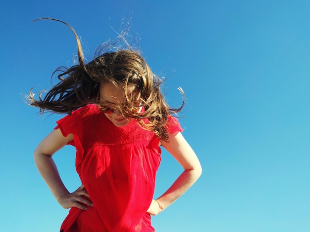 low angle view of girl standing against clear blue sky