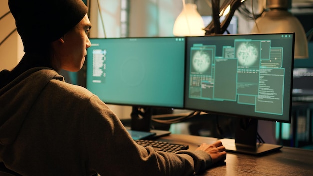 Male thief exploiting server vulnerability and breaking into firewall encryption, using hacktivism concept to steal information. Young man planting pc malware on computer system. Tripod shot.