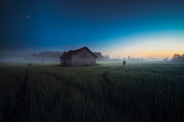 man by hut on field against sky at dusk