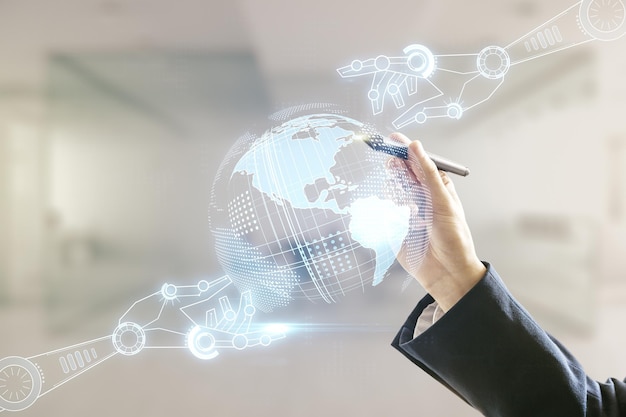 Man hand with pen working with abstract virtual robotics technology hologram with globe sketch on blurred office background Robot development and automation concept Multiexposure
