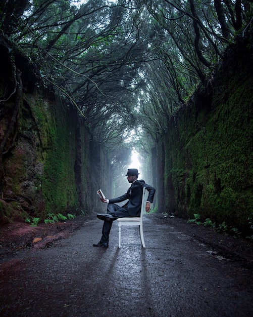 man sitting on road amidst trees