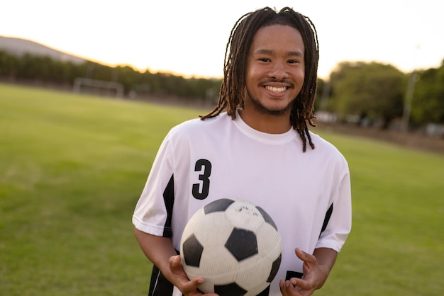 man standing on soccer field at sunset wearing white jersey 3 holding soccer ball copy space