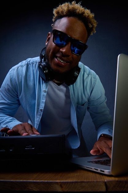 Man with curly head dj closeup at the dj console poses for a photographer