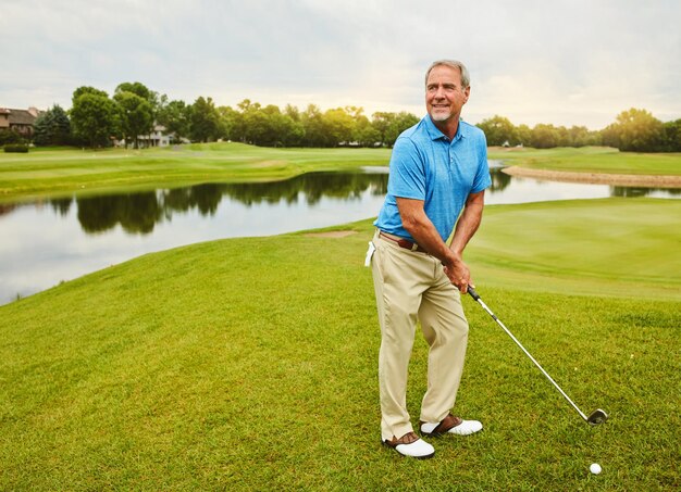 mature man and stroke on golf course or outdoor with club for mental focus skill and precision or training for tournament male golfer lake and thoughts for game plan shot strategy and exercise