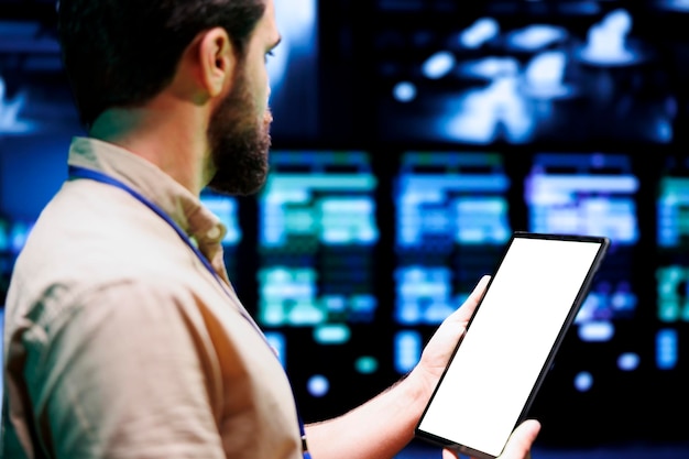 Meticulous IT programmer using tablet to oversee supercomputer hub security features protecting against unauthorized access, data breaches, phishing attacks and other cybersecurity issues