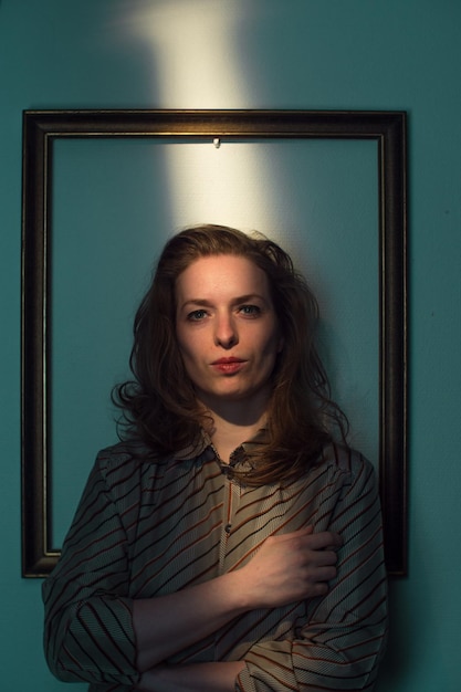 mid adult woman standing against picture frame on wall