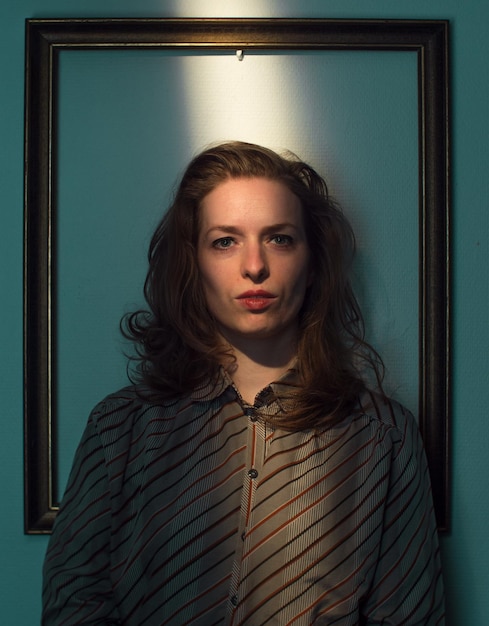 mid adult woman standing against picture frame on wall