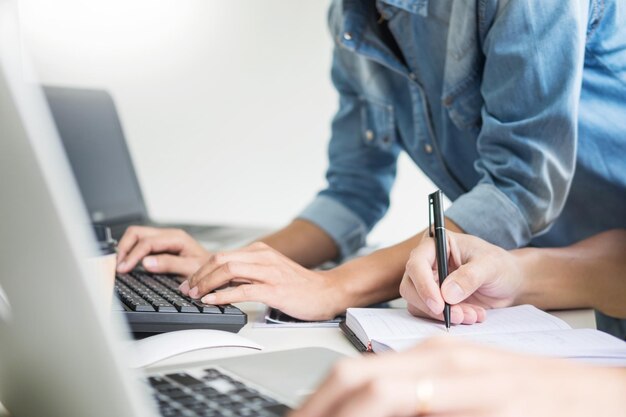 Midsection of colleagues using laptops in office