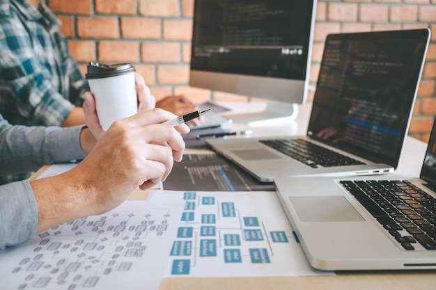 Midsection of colleagues using laptops on table