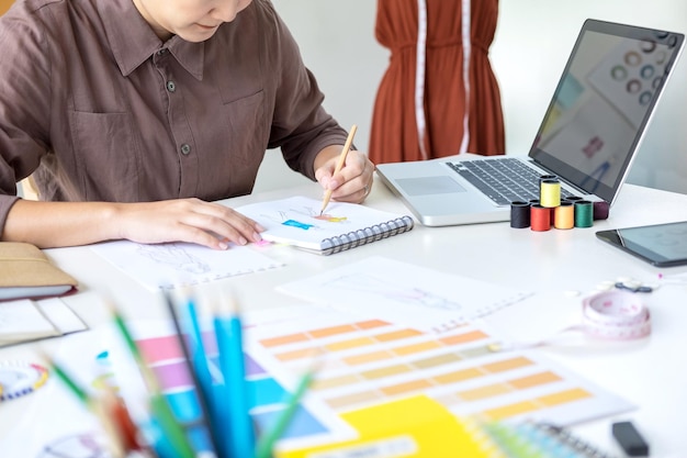 Midsection of fashion designer making sketch at desk