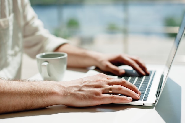 midsection of man using laptop while having coffee at table in cafe