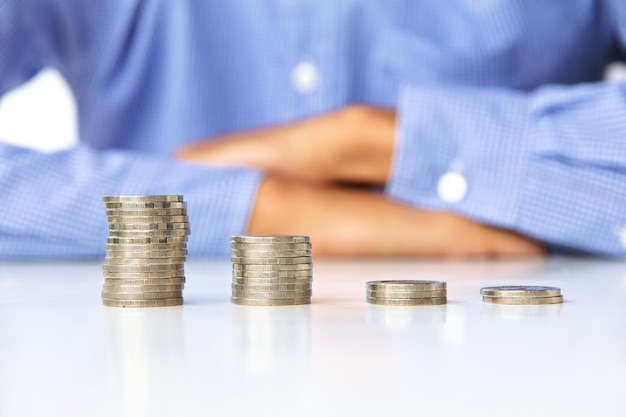 midsection of man with stack on coins on table