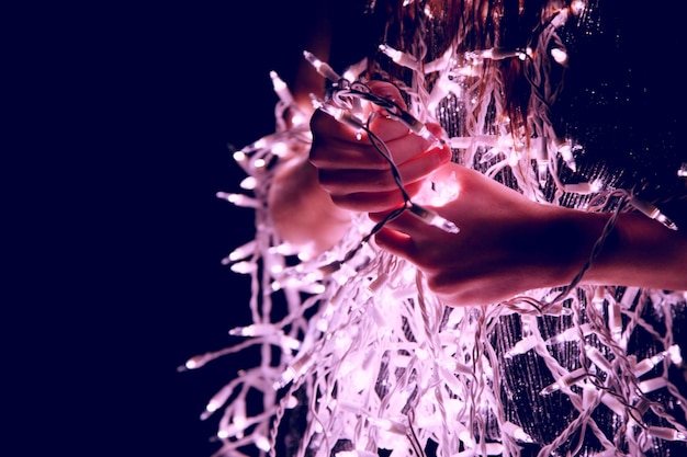 Midsection of woman with string lights at night