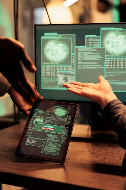 modern hackers trying to crack firewall encryption on tablet, working at night with computers to steal data. planting malware and hacking network server online, phishing concept.