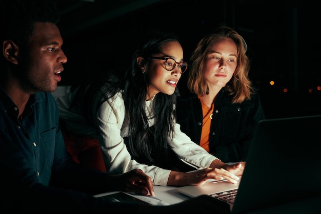 Multiethnic group of business people working with laptop late at night in their office