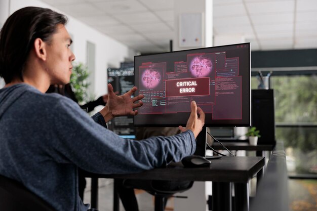 nervous app developer having system error message on computer screen, trying to solve hacking alert problem. system engineer looking at hacked server on pc monitor in it office room.
