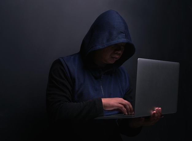 network hacker and man with laptop in studio for cybersecurity malware and scam on database cyber attack crime and person with technology for fraud coding risk and ransomware on black background