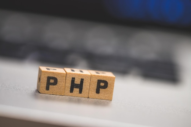 Ngôn ngữ lập trình web PHP. Các khối gỗ có chữ PHP nằm trên máy tính xách tay